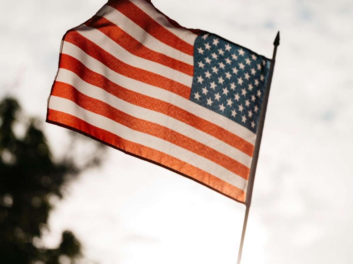 A law firm manager in Boston auditing legal mail for USPS stamp compliance, using a UV light to check the authenticity of Forever stamps.