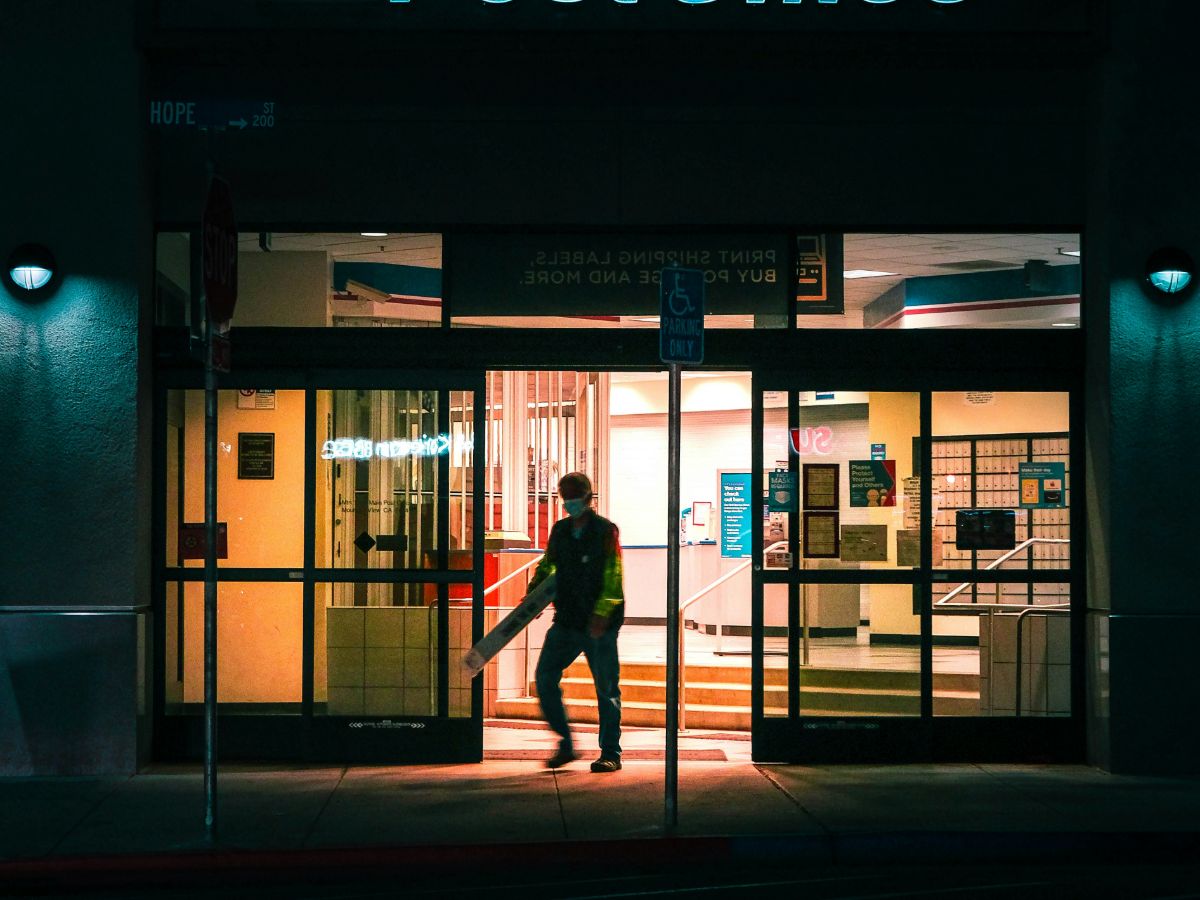 A Chicago small business owner in his office auditing a batch of promotion kits and applying stamps with a usps business stamp account discount with the city skyline in the background.