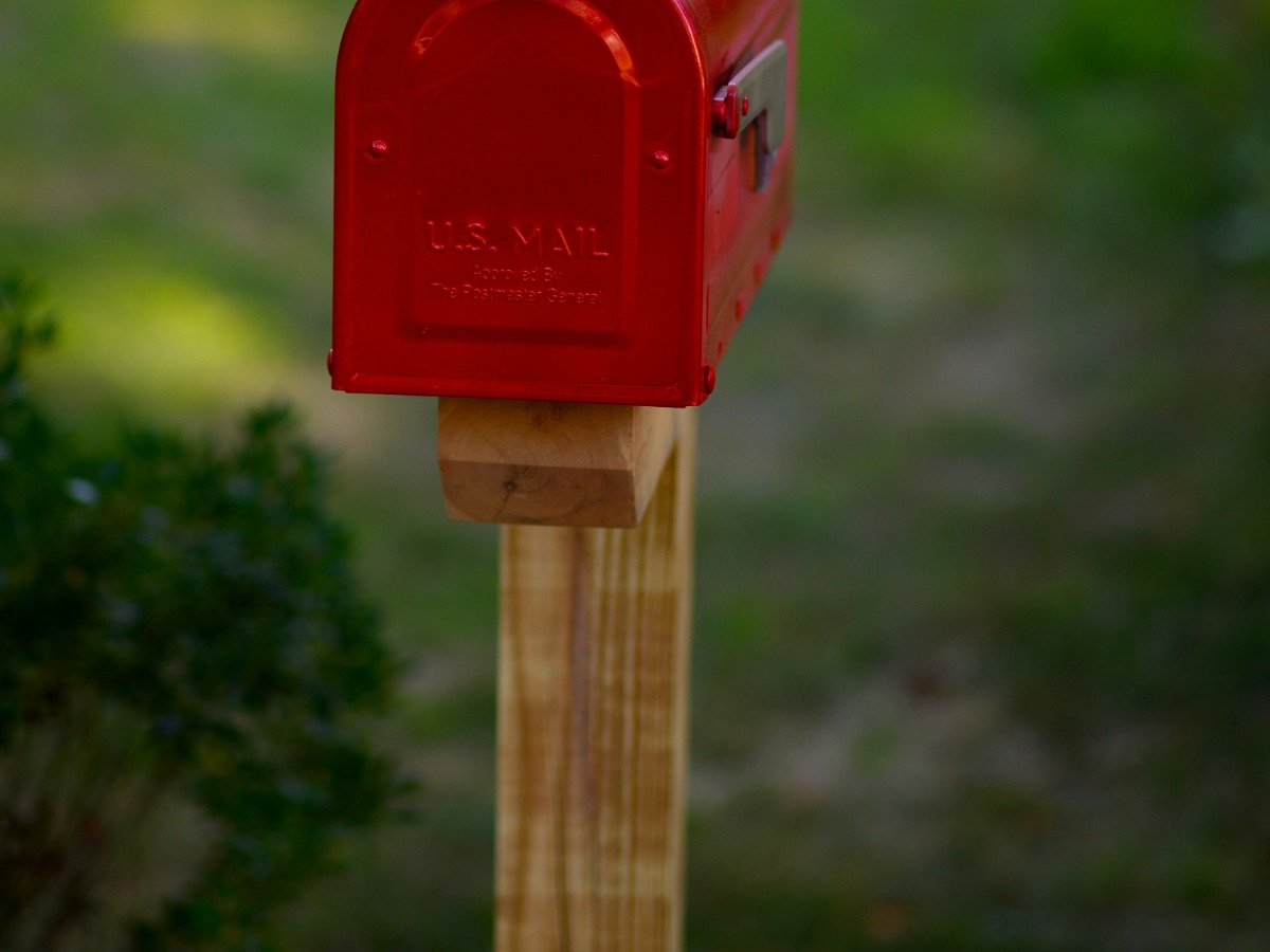 An Austin marketing agency founder in her office auditing a batch of direct mail campaign packets and applying forever stamps from a professional coil with the city skyline in the background.